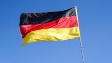 German national flag waving prominently against a bright blue sky in Lüneburg, Germany.